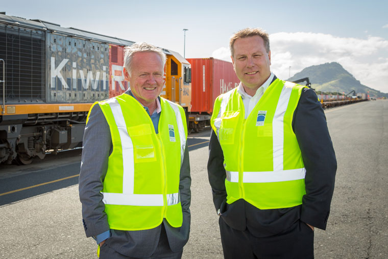 Two men in hi-vis vests in front of a train.